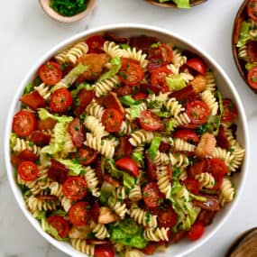 30-Minute BLT Pasta Salad in a large white serving bowl next to wooden serving spoons