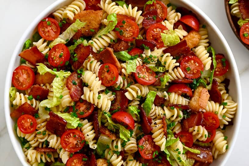 30-Minute BLT Pasta Salad in a large white serving bowl next to wooden serving spoons