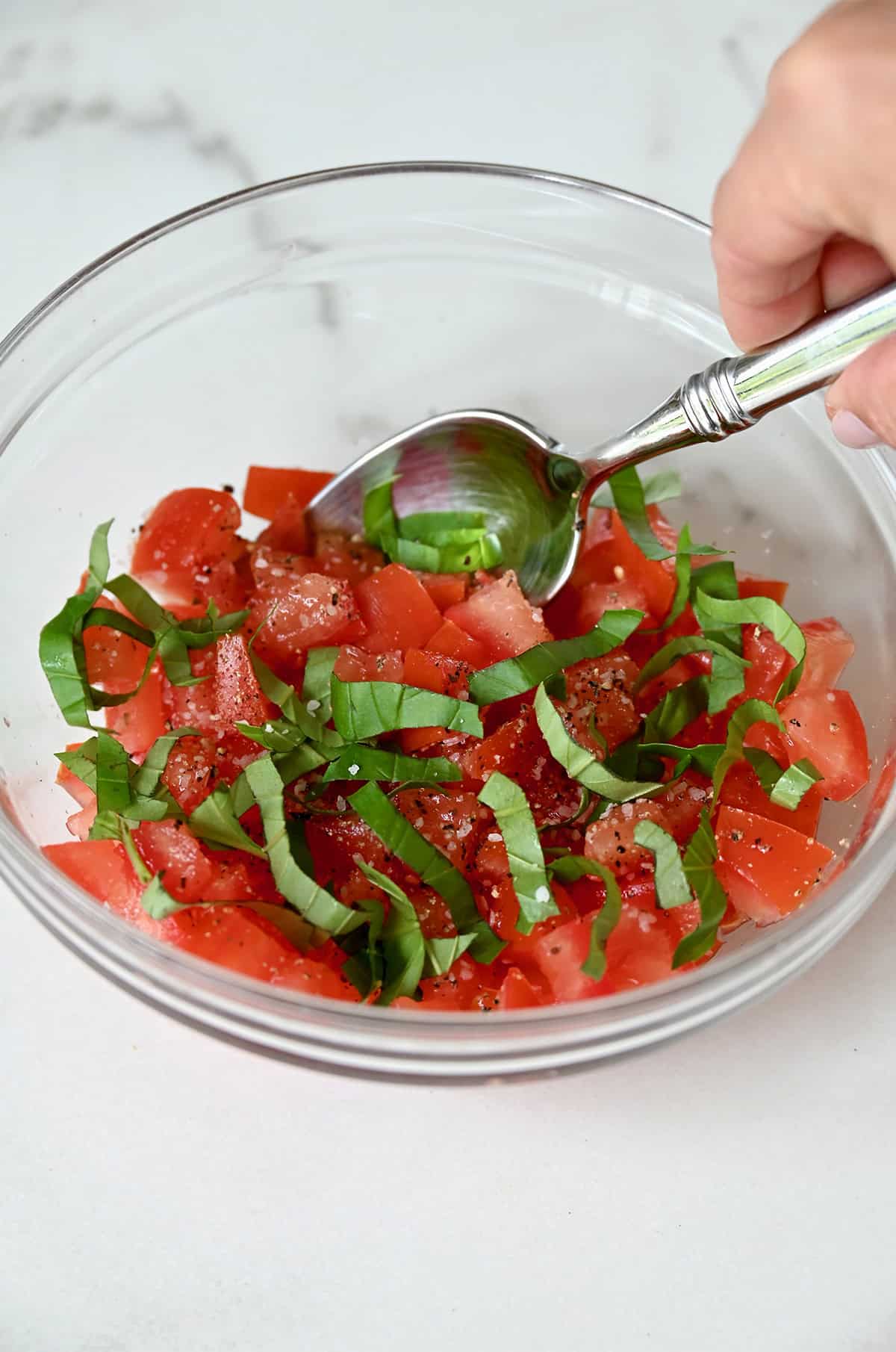 Diced tomatoes and chopped fresh basil in a bowl.