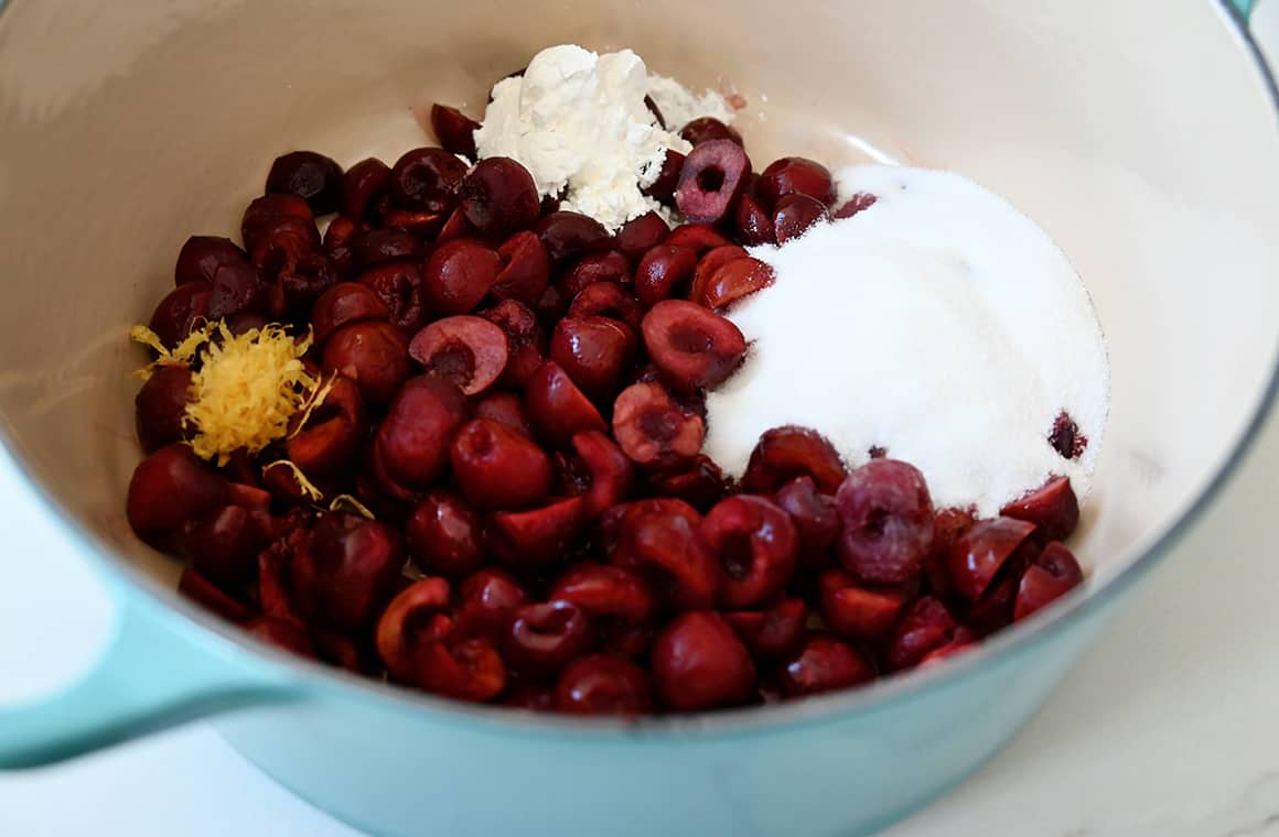 A large saucepan containing fresh cherries, sugar, cornstarch, vanilla extract and lemon zest