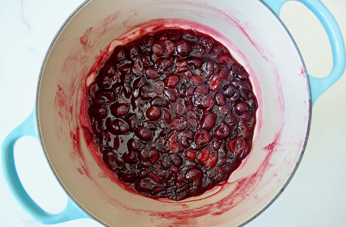 A top-down view of fresh cherry pie filling in a large saucepan