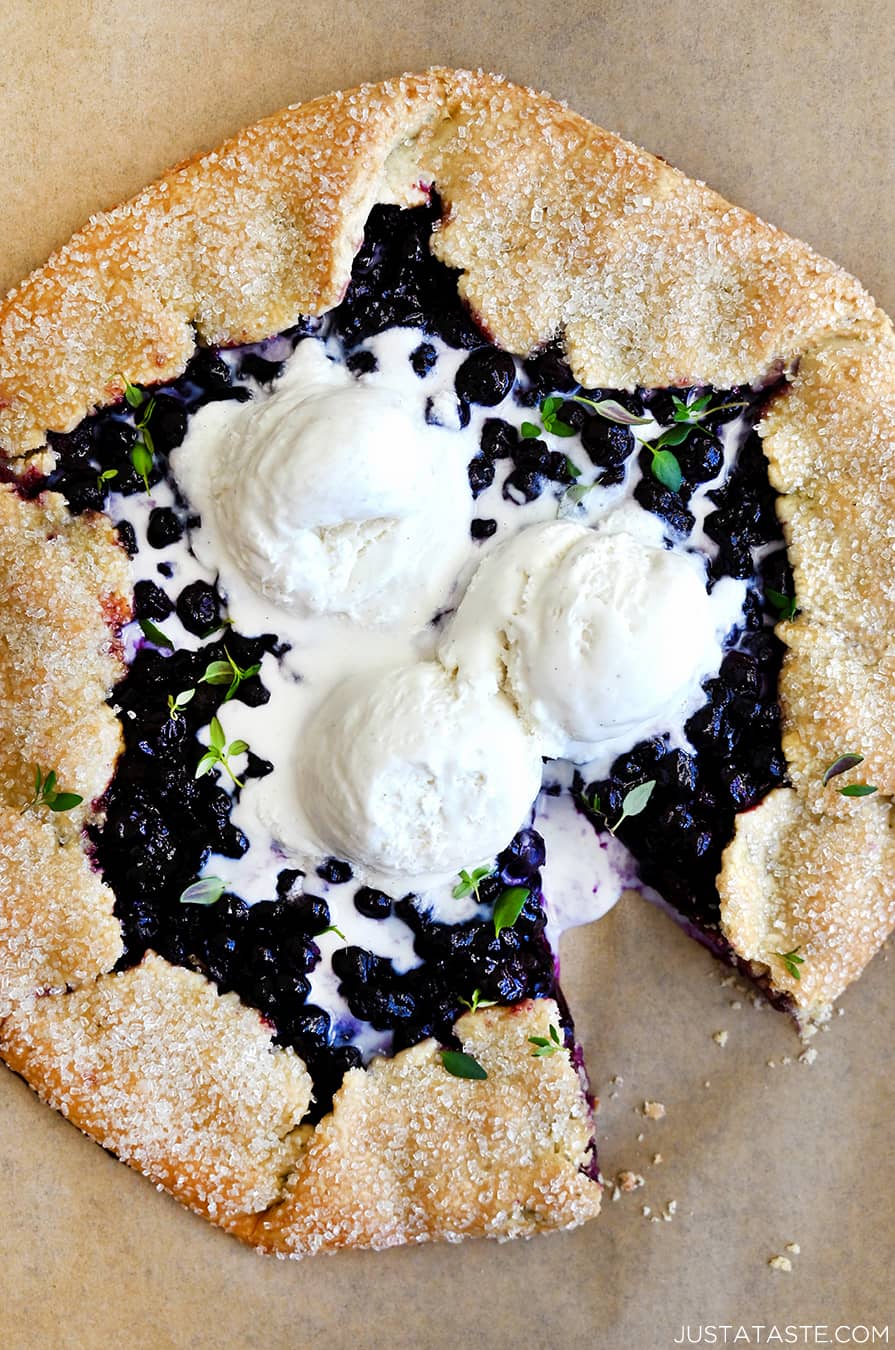 A top-down view of a Blueberry Galette topped with three scoops of vanilla bean ice cream and fresh thyme