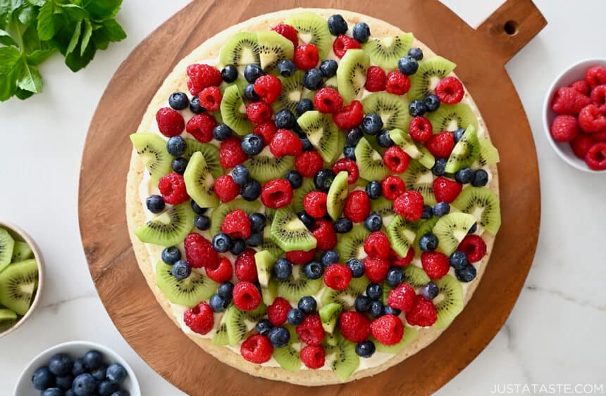 A top-down view of the best homemade Fruit Pizza with a sugar cookie crust atop a wood serving board