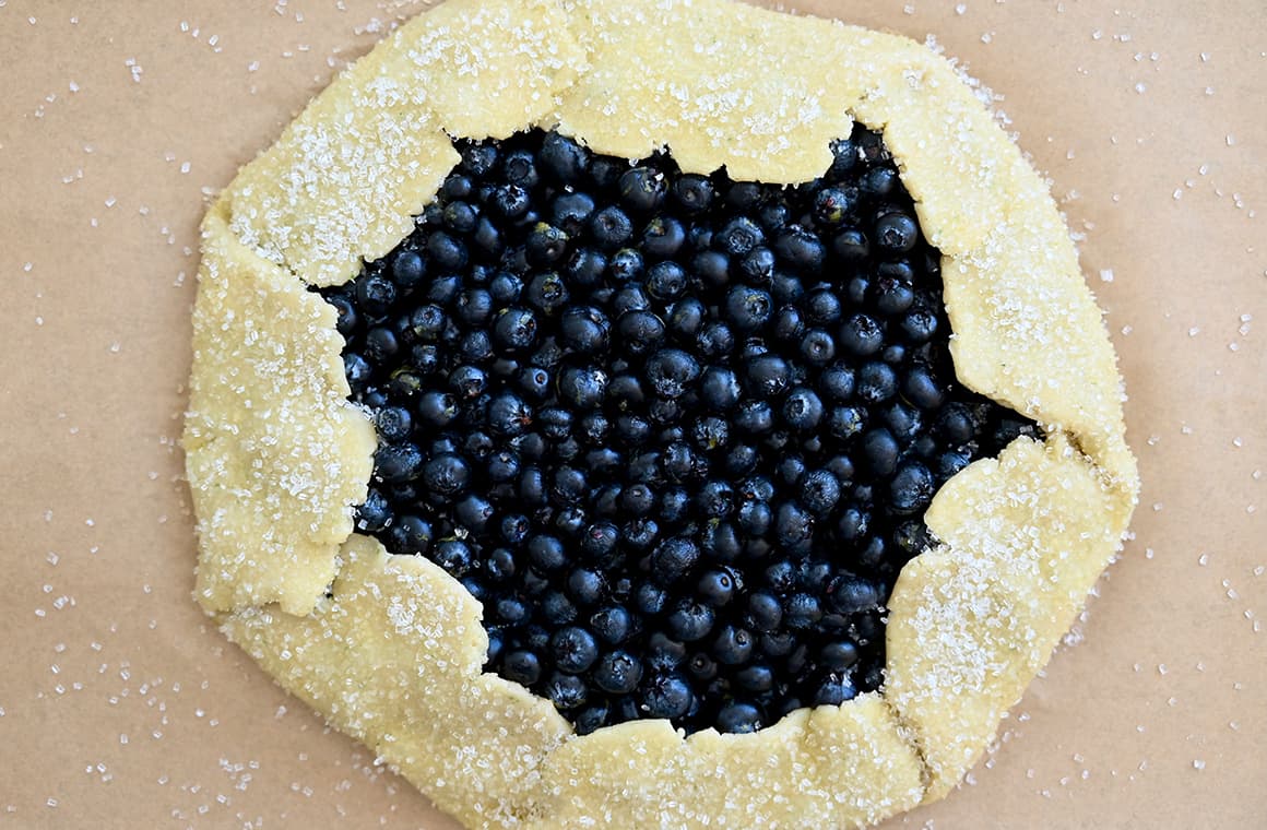 A top-down view of an unbaked berry pie sprinkled with sanding sugar