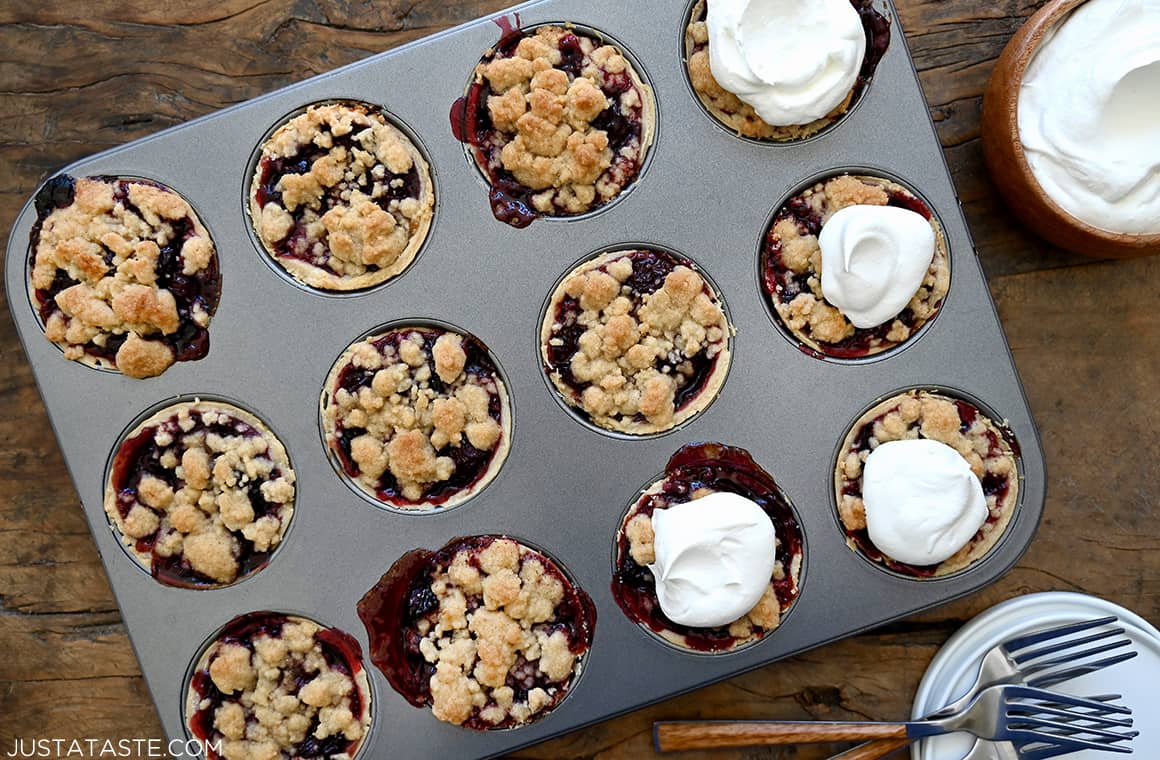 Homemade muffin tin Mini Cherry Pies topped with streusel and whipped cream