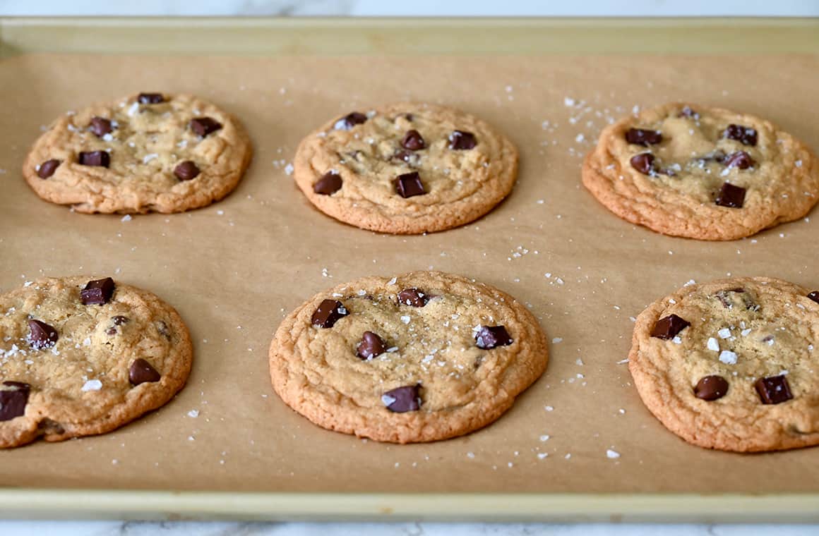 Freshly baked cookies on a parchment paper-lined baking sheet sprinkled with sea salt