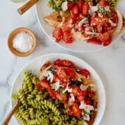 Quick Bruschetta Chicken on a dinner plate with pesto pasta and a fork.