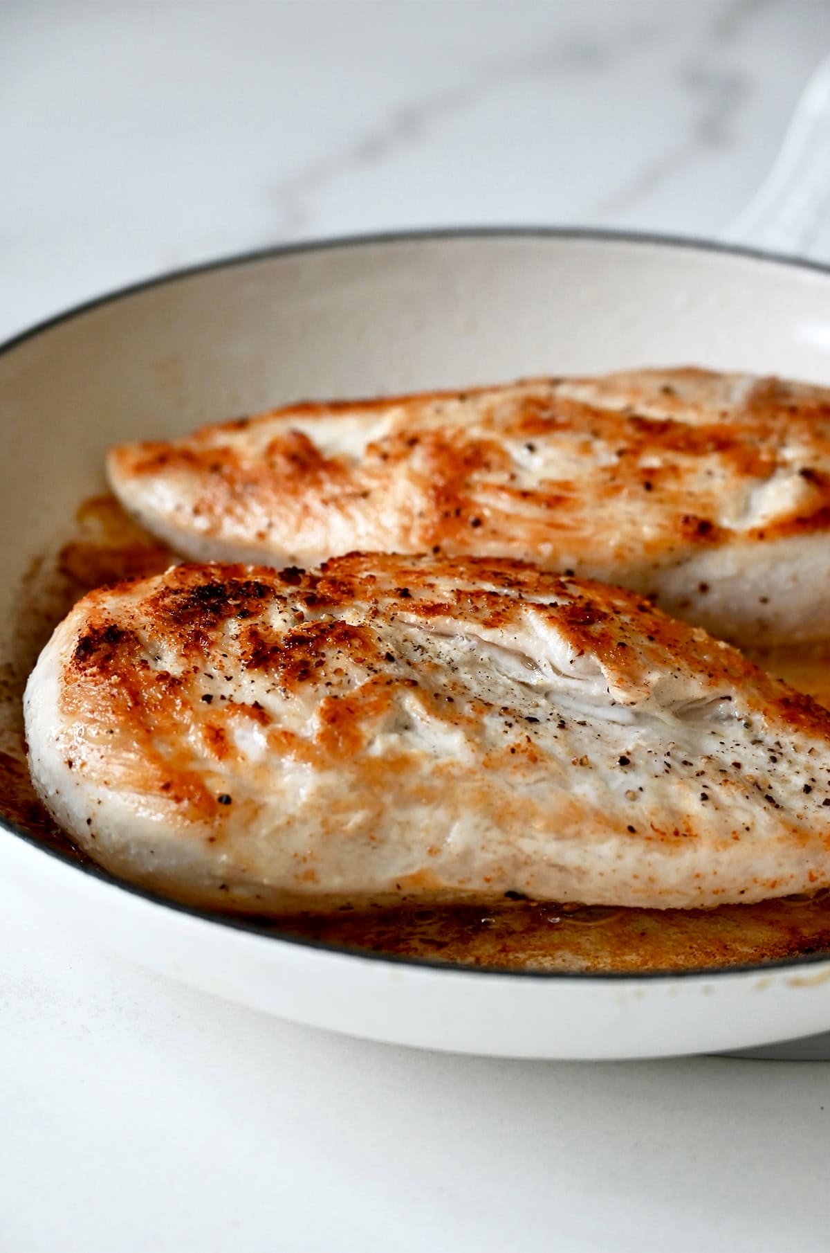 Seared chicken breasts in a skillet.