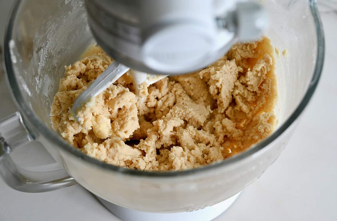 A top-down view of a stand mixer bowl containing sugar cookie dough