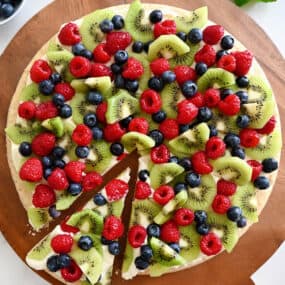 A top-down view of Sugar Cookie Fruit Pizza on a wood serving board