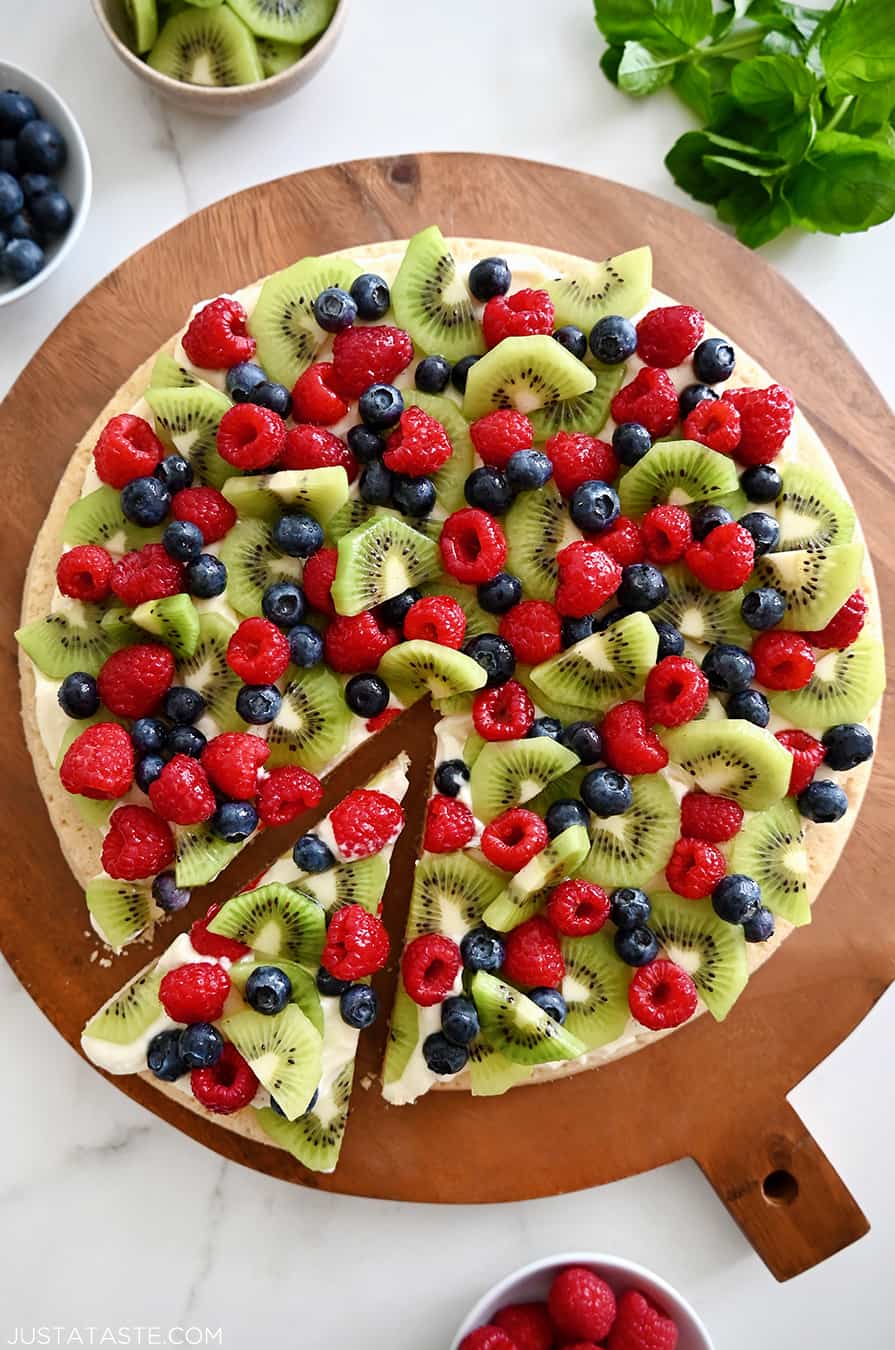 A top-down view of Sugar Cookie Fruit Pizza on a wood serving board