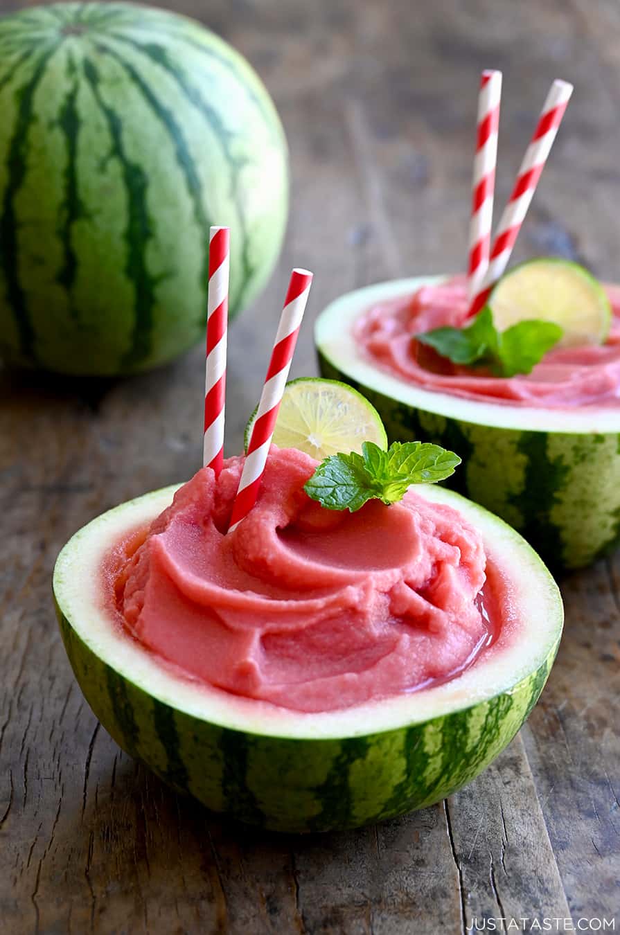 Watermelon Slushies in a half hollowed-out watermelon with a straw and a lime wedge garnish