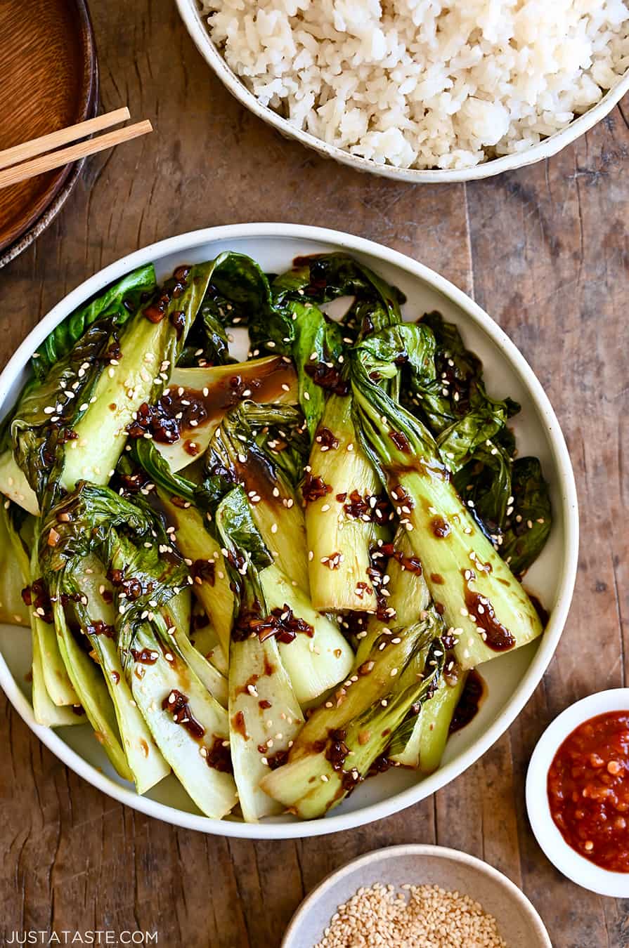 A white bowl with bok choy drizzled with soy sauce