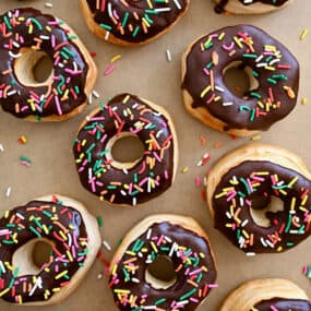 A top-down view of Air Fryer Biscuit Doughnuts topped with chocolate glaze and rainbow sprinkles