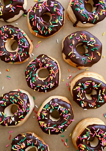 A top-down view of Air Fryer Biscuit Doughnuts topped with chocolate glaze and rainbow sprinkles