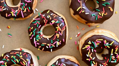 A top-down view of Air Fryer Biscuit Doughnuts topped with chocolate glaze and rainbow sprinkles