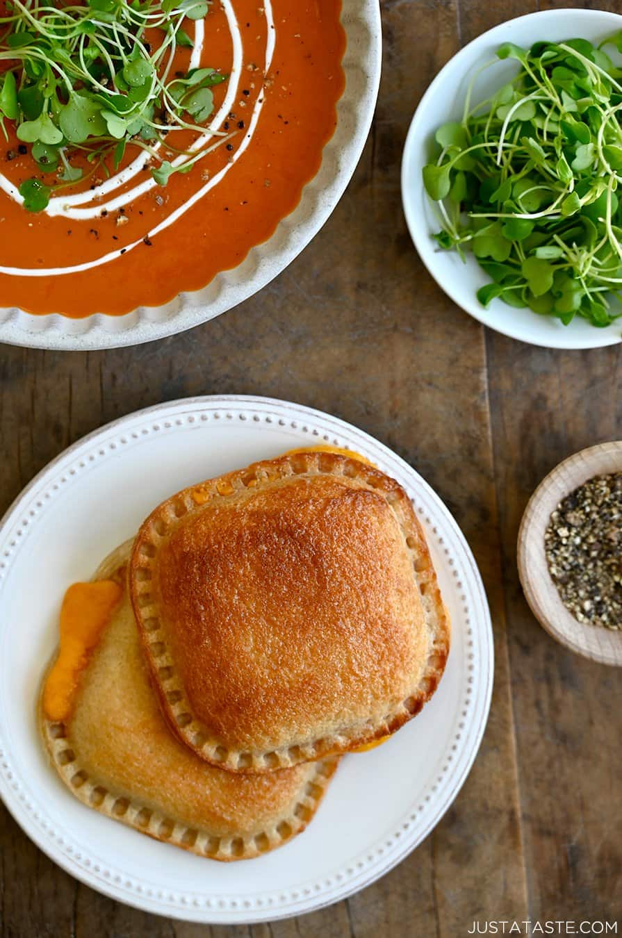 A top down view of two grilled cheese sandwiches next to a bowl of tomato soup