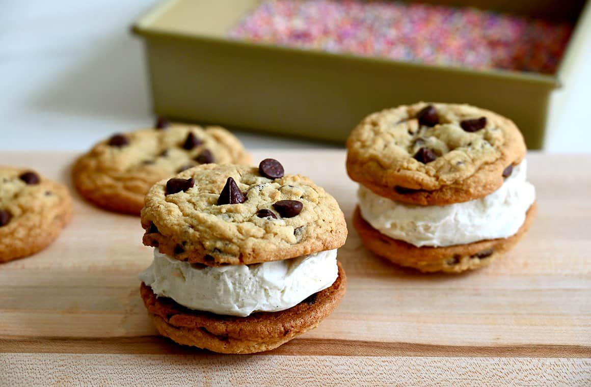 A wood cutting board containing chocolate chip cookie ice cream sandwiches