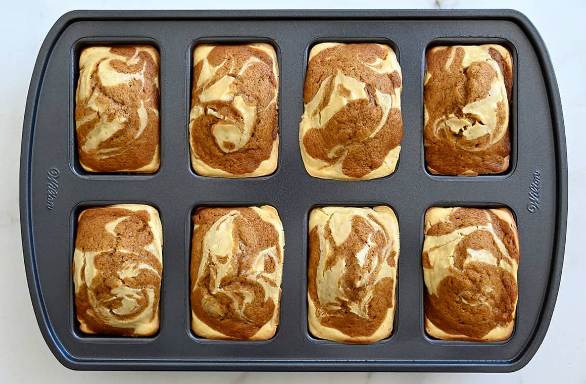 A top-down view of a mini loaf pan with freshly baked mini pumpkin cheesecake loaves