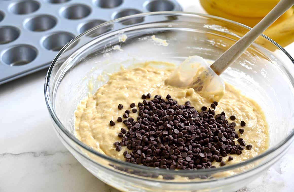 A clear bowl containing batter and mini chocolate chips