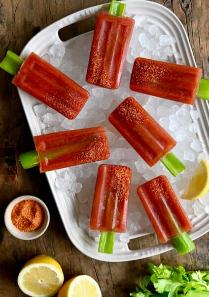 A top-down view of Bloody Mary Popsicles with celery sticks over ice