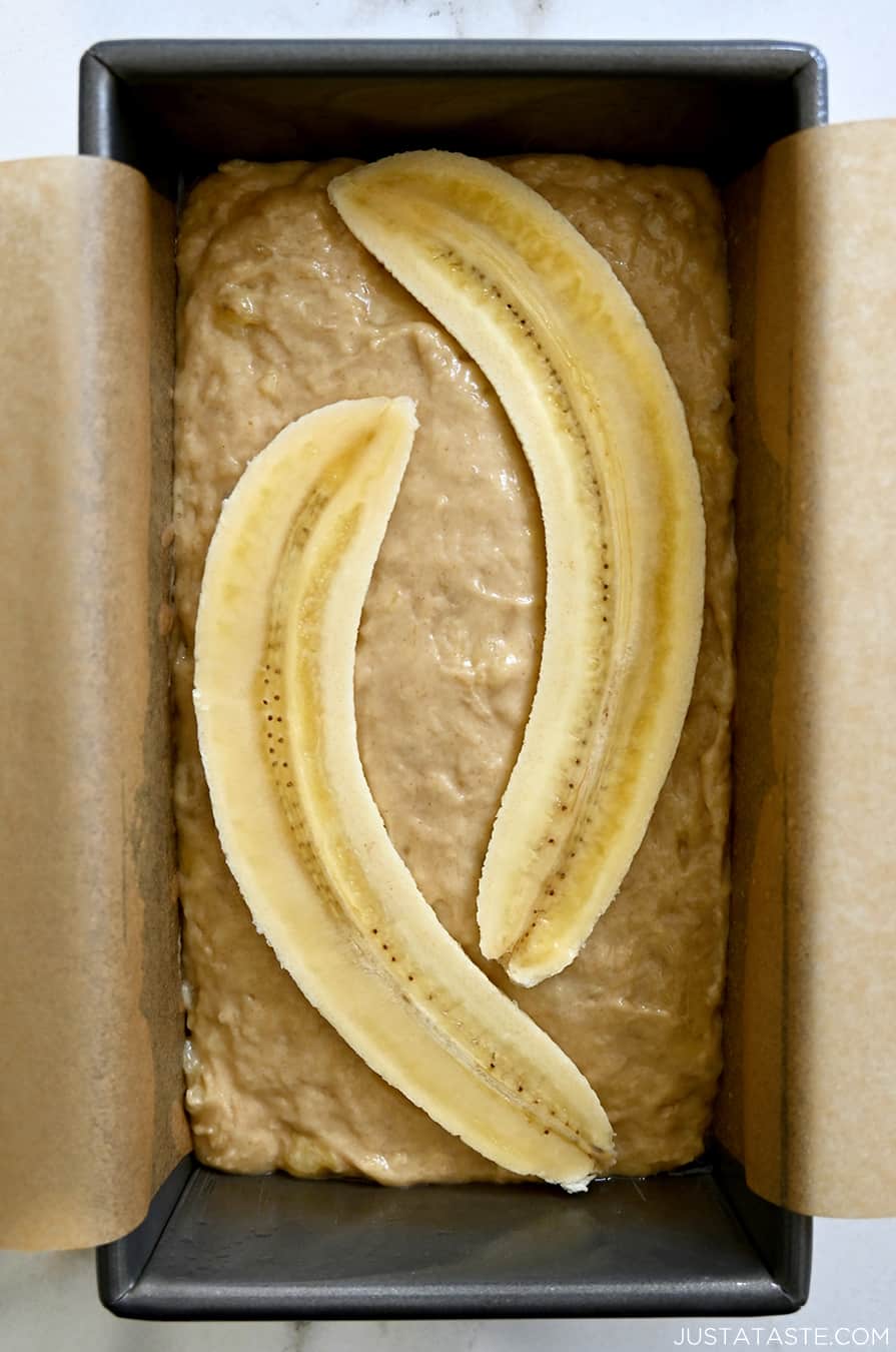 A top-down view of unbaked batter in a loaf pan lined with parchment paper