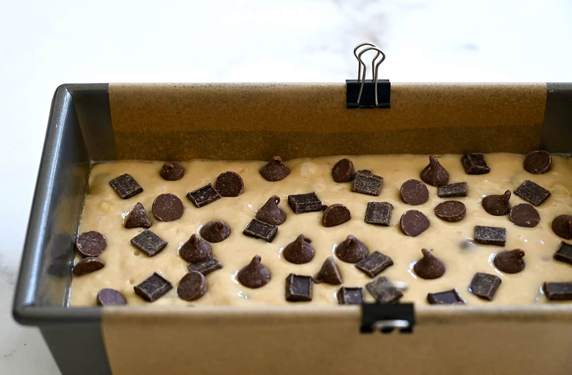 A loaf pan lined with parchment paper secured with metal paper clips