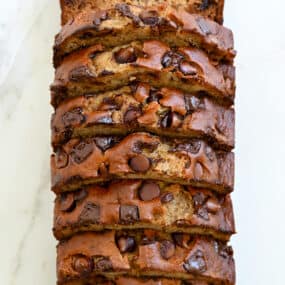 A top-down view of a sliced loaf of Buttermilk Banana Bread studded with chocolate chunks