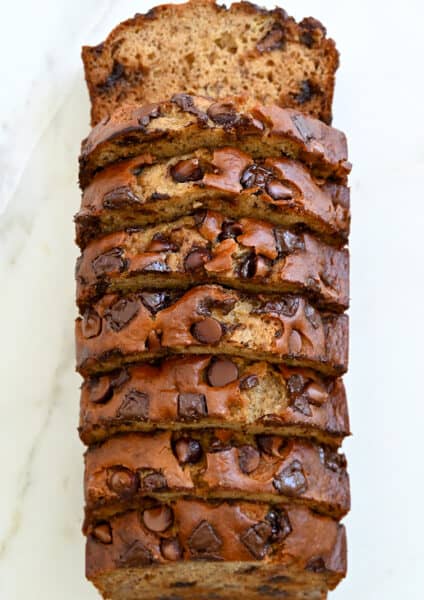 A top-down view of a sliced loaf of Buttermilk Banana Bread studded with chocolate chunks