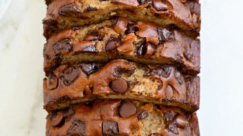 A top-down view of a sliced loaf of Buttermilk Banana Bread studded with chocolate chunks
