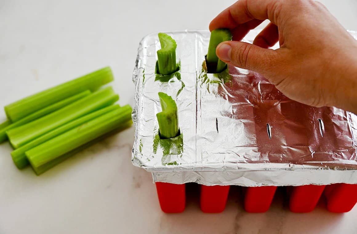 Celery sticks being inserted into each boozicle mold