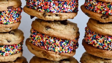Three tall stacks of chocolate chip cookie ice cream sandwiches coated in rainbow sprinkles