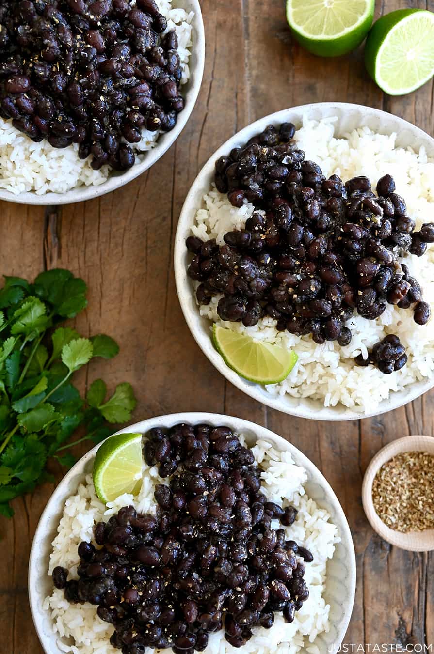 A top-down view of three bowls containing Quick Cuban Black Beans over white rice