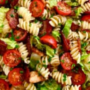 A close-up view of BLT pasta salad tossed in a red wine vinaigrette and garnished with chopped fresh chives.