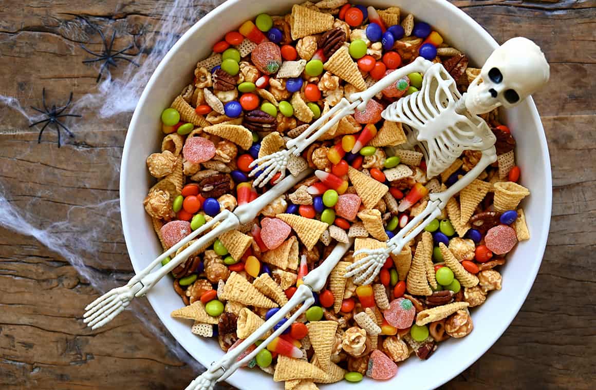 Il miglior mix di spuntini dolci e salati di Halloween in una grande ciotola da portata con uno scheletro di plastica