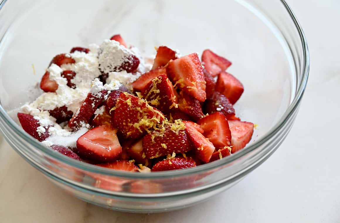 Sliced strawberries, lemon zest, sugar and cornstarch in a clear bowl