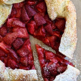 A top-down view of a strawberry puff pastry galette dusted with powered sugar