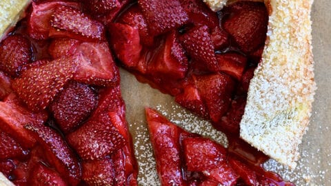 A top-down view of a strawberry puff pastry galette dusted with powered sugar