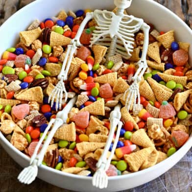 A white bowl containing easy Halloween Snack Mix and a small plastic skeleton
