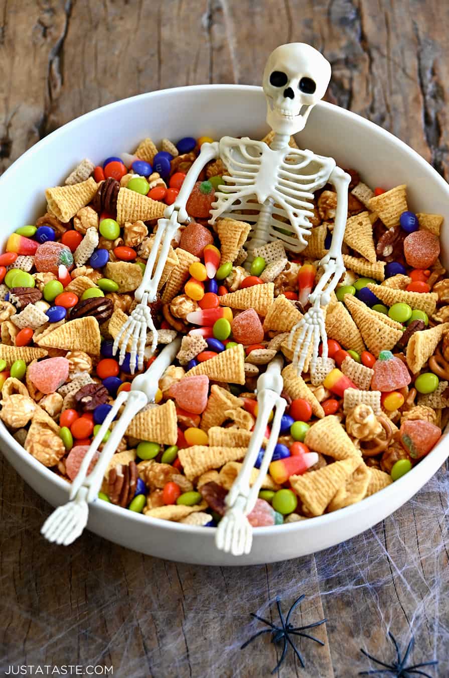 A white bowl containing easy Halloween Snack Mix and a small plastic skeleton