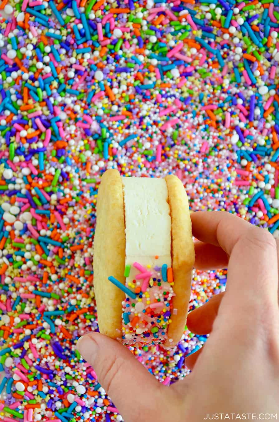An ice cream sandwich being rolled in sprinkles