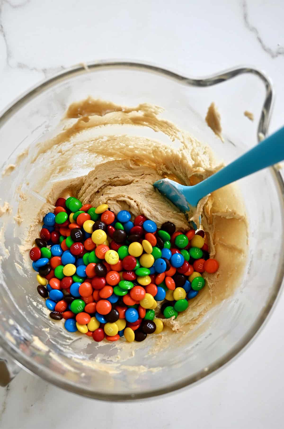 M&M cookie dough in a bowl with a spatula.