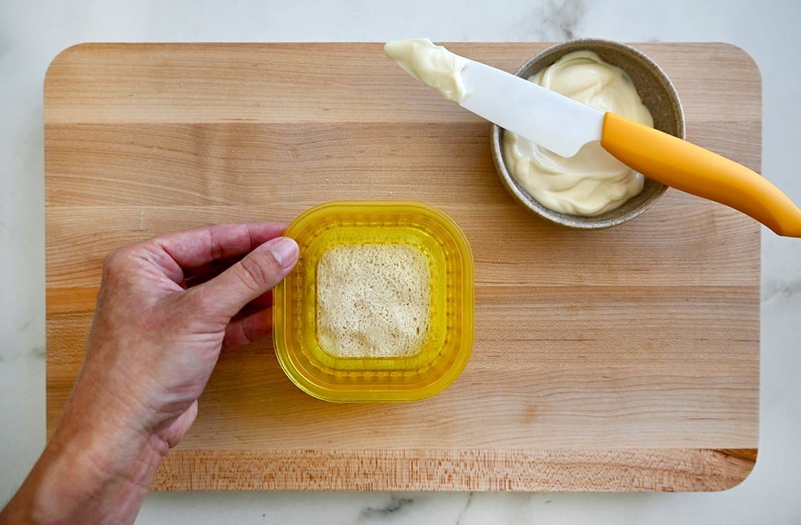 A wood cutting board topped with a grilled cheese Uncrustable sandwich