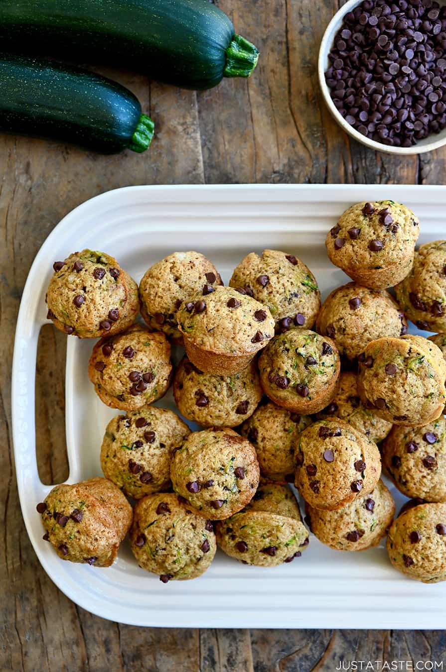 A top-down view of Mini Zucchini Muffins piled high on a white serving platter