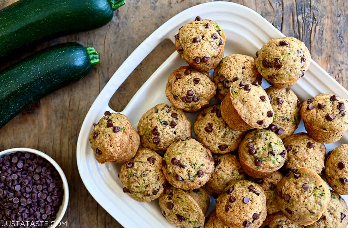 Mini Chocolate Chip Zucchini Muffins on a white serving platter next to a small bowl filled with mini chocolate chips