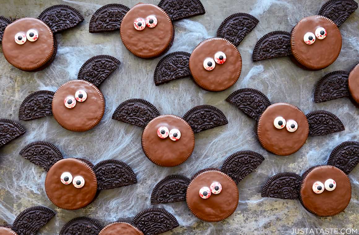 A top-down view of bat Oreo cookies with candy eyes atop fake cobweb