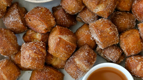 A top-down view of Pumpkin Spice Pretzel Bites surrounding a small bowl containing whipped cream and a small bowl containing caramel sauce