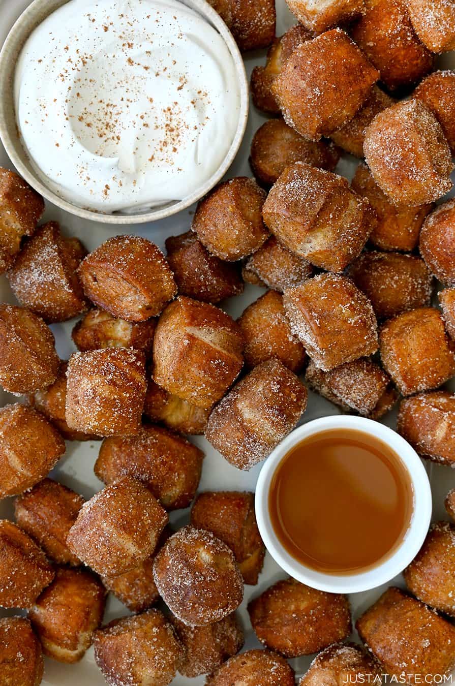 A top-down view of Pumpkin Spice Pretzel Bites surrounding a small bowl containing whipped cream and a small bowl containing caramel sauce