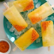 A top-down view of margarita popsicles garnished with Tajin seasoning over ice in a bowl.