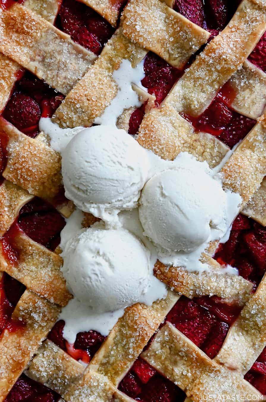 A close-up view of a homemade strawberry slab pie and lattice with three scoops of vanilla ice cream